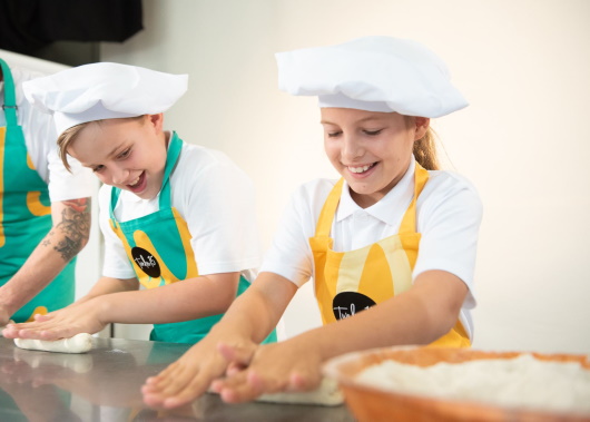 Girl and boy wearing chef clothing making bread 